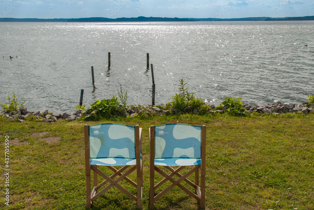 Zwei leere Gartenstühle am See