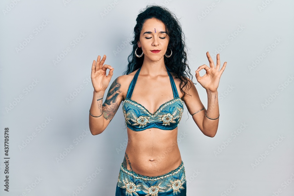 Young woman wearing bindi and traditional belly dance clothes relaxed and smiling with eyes closed doing meditation gesture with fingers. yoga concept.