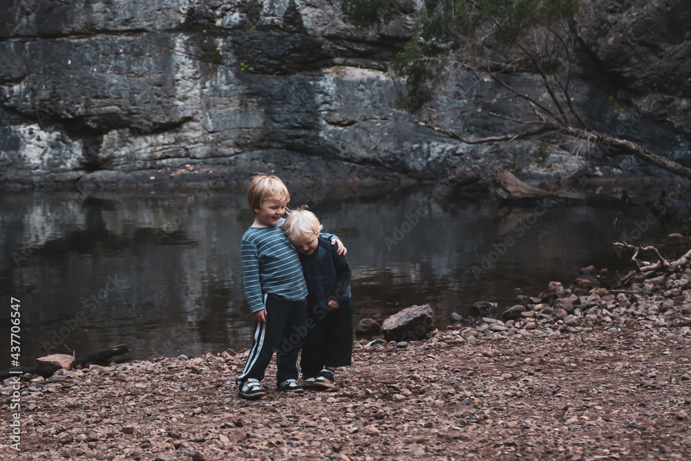 Fototapeta premium Two little boys standing together in front of rock pool on outdoor adventure