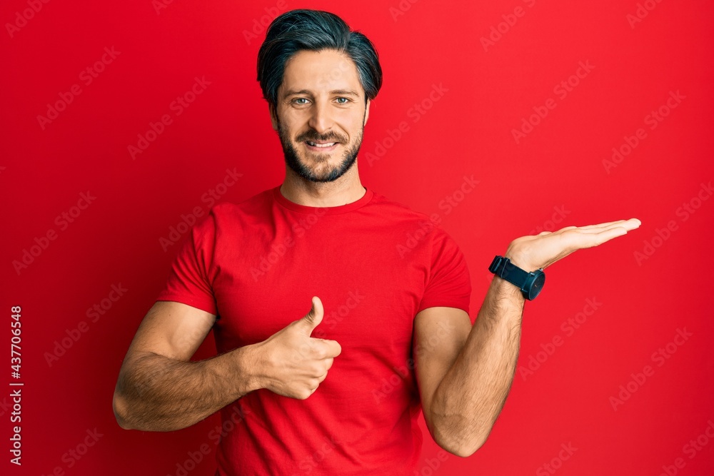 Young hispanic man wearing casual red t shirt showing palm hand and doing ok gesture with thumbs up, smiling happy and cheerful Young hispanic man wearing casual red t shirt showing palm hand and doing ok gesture with thumbs up, smiling happy and cheerful