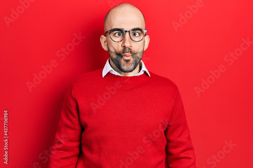 Young bald man wearing casual clothes and glasses making fish face with lips, crazy and comical gesture. funny expression.