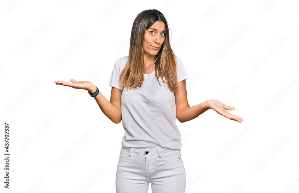 Young woman wearing casual white t shirt clueless and confused expression with arms and hands raised. doubt concept. Young woman wearing casual white t shirt clueless and confused expression with arms and hands raised. doubt concept.