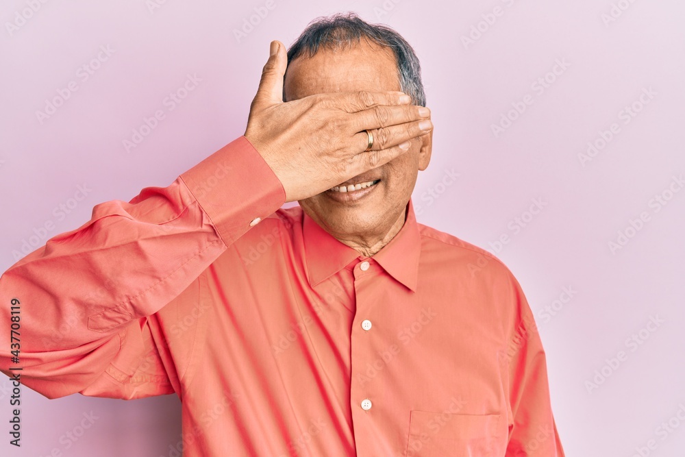 Middle age indian man wearing casual clothes and glasses smiling and laughing with hand on face covering eyes for surprise. blind concept. Middle age indian man wearing casual clothes and glasses smiling and laughing with hand on face covering eyes for surprise. blind concept.