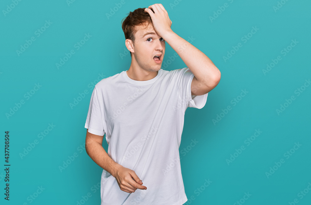 Young caucasian man wearing casual white t shirt surprised with hand on head for mistake, remember error. forgot, bad memory concept. Young caucasian man wearing casual white t shirt surprised with hand on head for mistake, remember error. forgot, bad memory concept.
