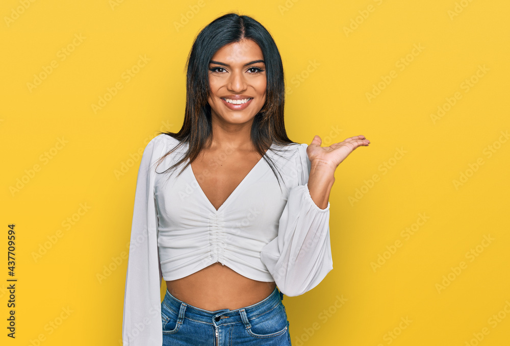 Young latin transsexual transgender woman wearing casual clothes smiling cheerful presenting and pointing with palm of hand looking at the camera. Young latin transsexual transgender woman wearing casual clothes smiling cheerful presenting and pointing with palm of hand looking at the camera.