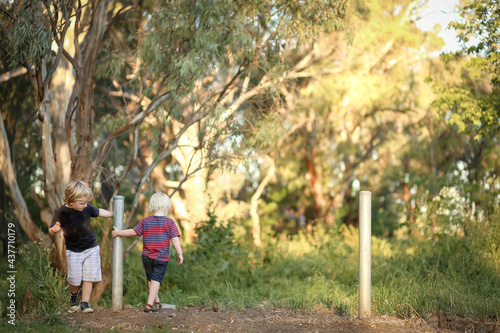 Little boys spinning around fence post in the Australian bush