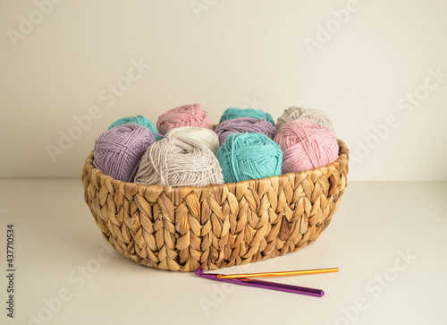 pastell coloured woolen balls in a basket with crochet hooks for crocheting and handicraft