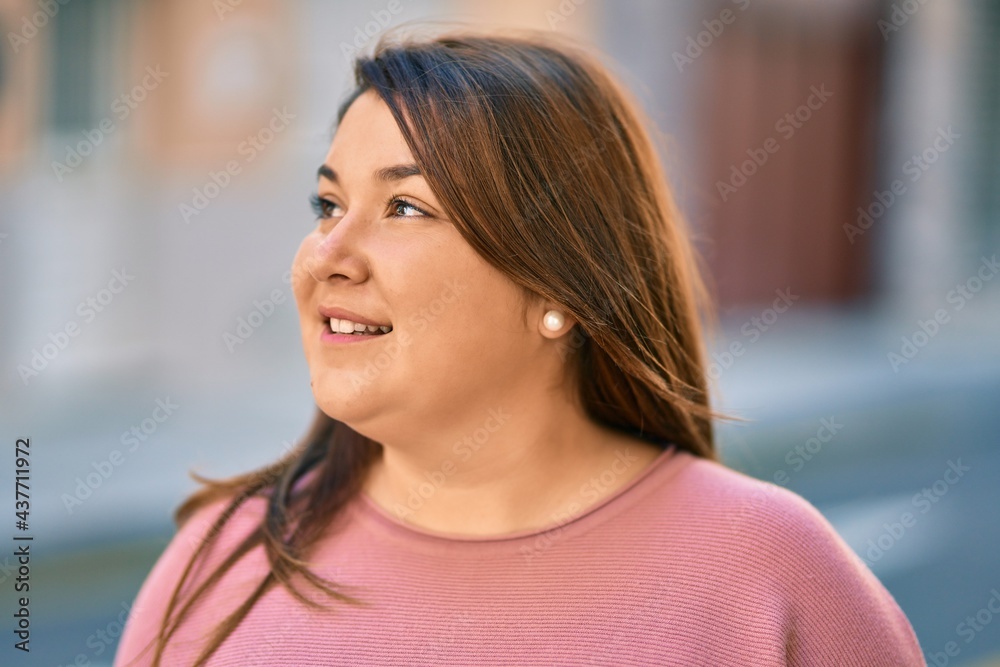 Young hispanic plus size woman smiling happy standing at the city.