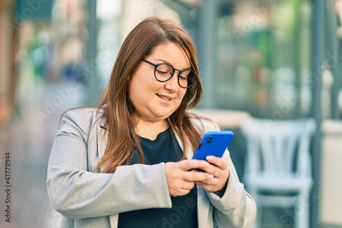 Young plus size businesswoman smiling happy using smartphone at the city.