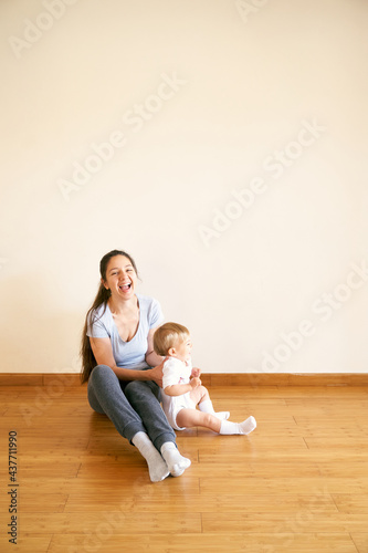 Smiling mom and little girl sitting on the floor