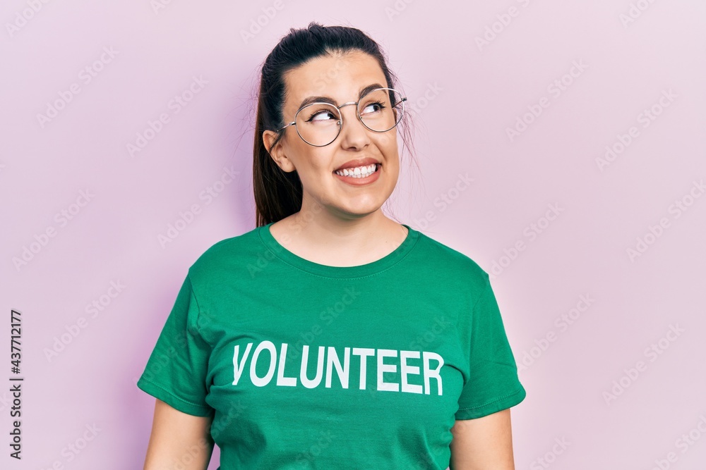 Young hispanic woman wearing volunteer t shirt smiling looking to the side and staring away thinking. Young hispanic woman wearing volunteer t shirt smiling looking to the side and staring away thinking.