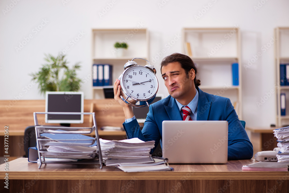 Young male employee in time management concept Young male employee in time management concept