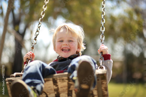 Little boy playing on swing set in old fashioned country playground