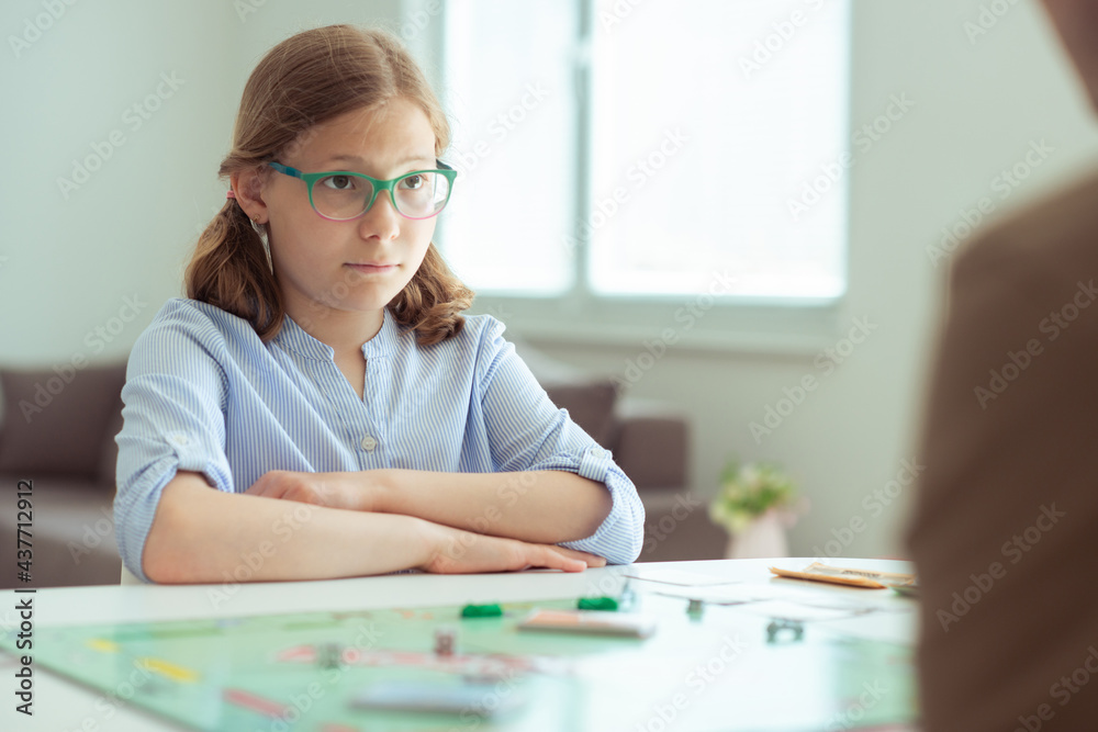 Portrait of pretty teen girl in glasses playing board game with parents Portrait of pretty teen girl in glasses playing board game with parents
