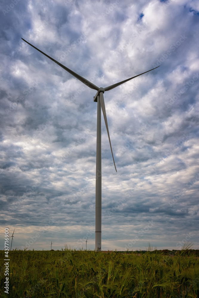 Electric generators located in countryside with beautiful landscape on background, wind turbines against cloudy sky, alternative energy resources Electric generators located in countryside with beautiful landscape on background, wind turbines against cloudy sky, alternative energy resources