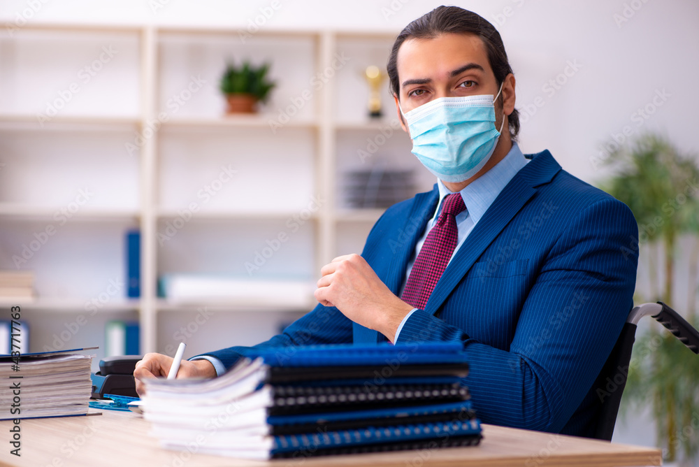 Young disabled employee during pandemic at workplace