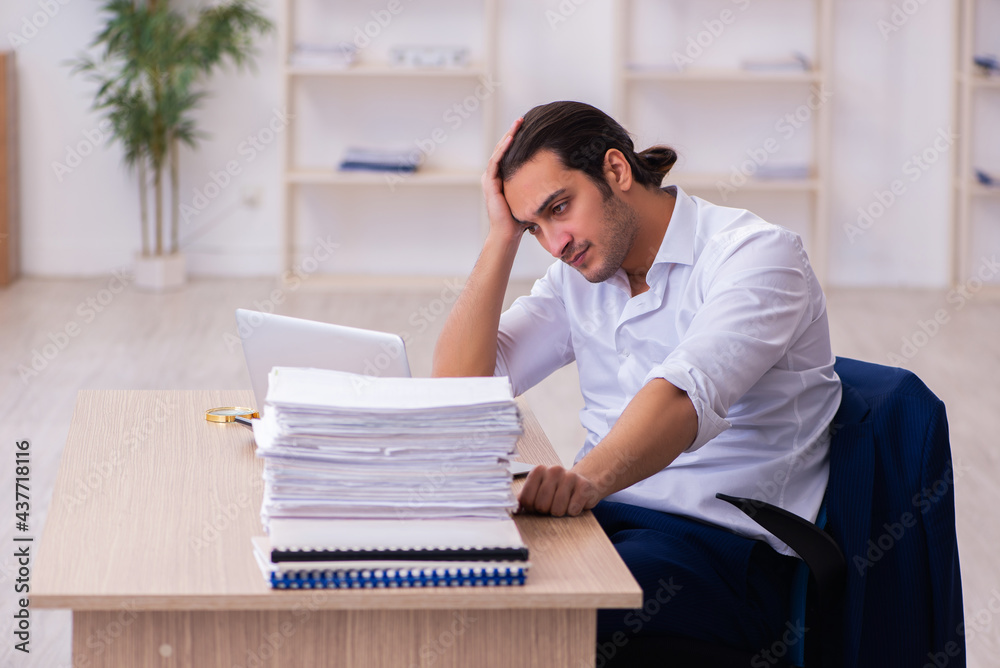 Young businessman employee unhappy with excessive work in the office Young businessman employee unhappy with excessive work in the office
