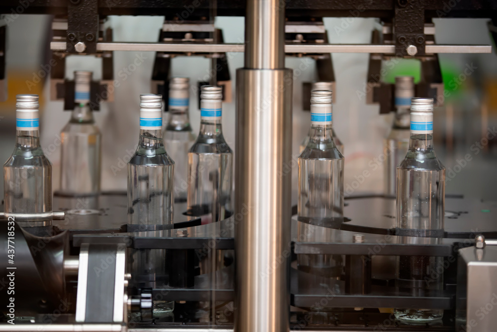 A long row of glass bottles on a conveyor belt. Production of alcoholic beverages. A long row of glass bottles on a conveyor belt. Production of alcoholic beverages.
