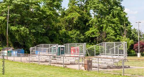 Empty metal bleacher seats next to a football field in Swissvale, Pennsylvania, USA on a sunny summer day