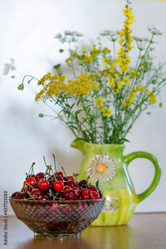 Summer still life - bowl of cherries and a bunch of wildflower s in a vase Summer still life - bowl of cherries and a bunch of wildflower s in a vase