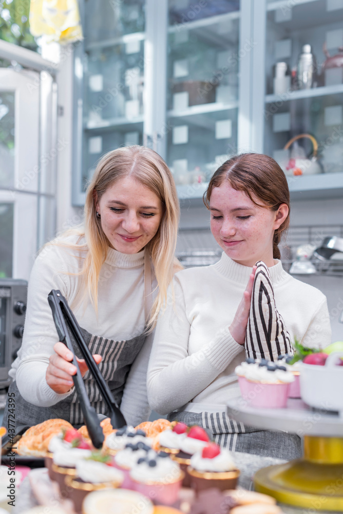 Smile and happy Caucasian Young Mother and Teenage Daughter looking at fresh baked delicious homemade croissants in kitchen
