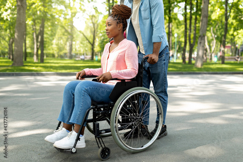 Obraz na plátně Disabled black woman in wheelchair on walk with her affectionate husband outdoor