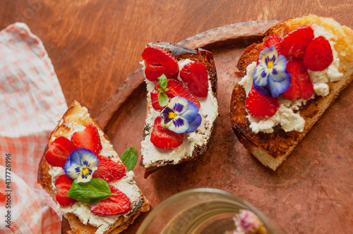 Strawberry toast brioche with cream cheese decorated with flowers and basil fflat lay close up photo