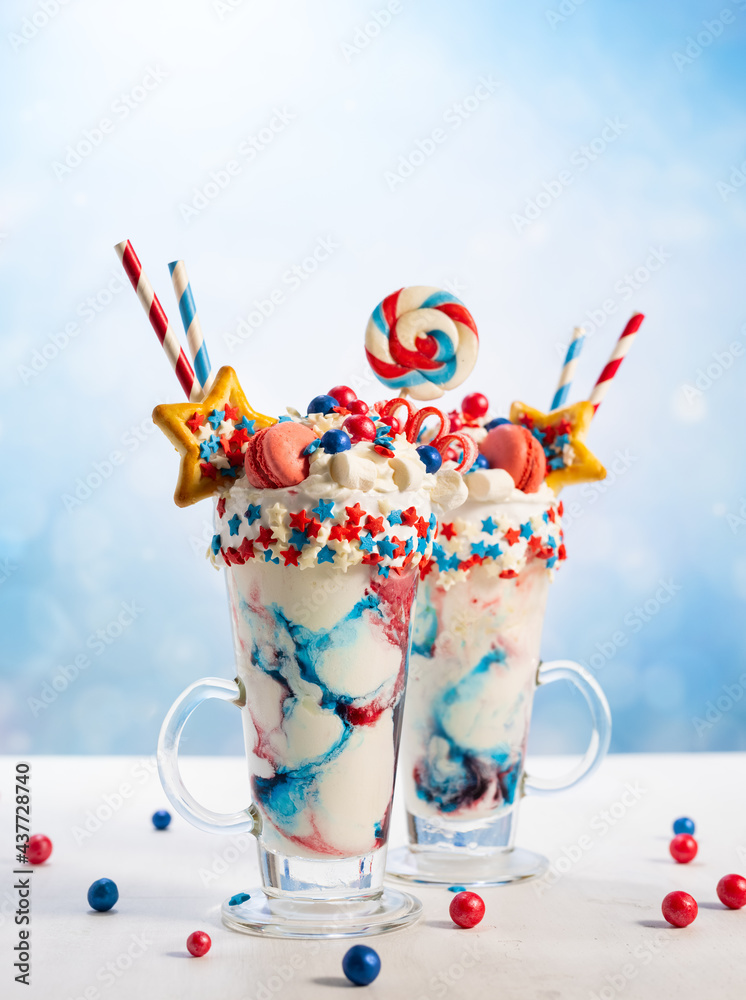 Crazy milk shake with ice cream,whipped cream, marshmallow,cookies and  colored candy in glass. Sweet dessert for Fourth of July. Idea milkshake  for Patriotic day. Photos | Adobe Stock