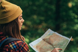 A hiker woman using map for orientation while walking in the forest