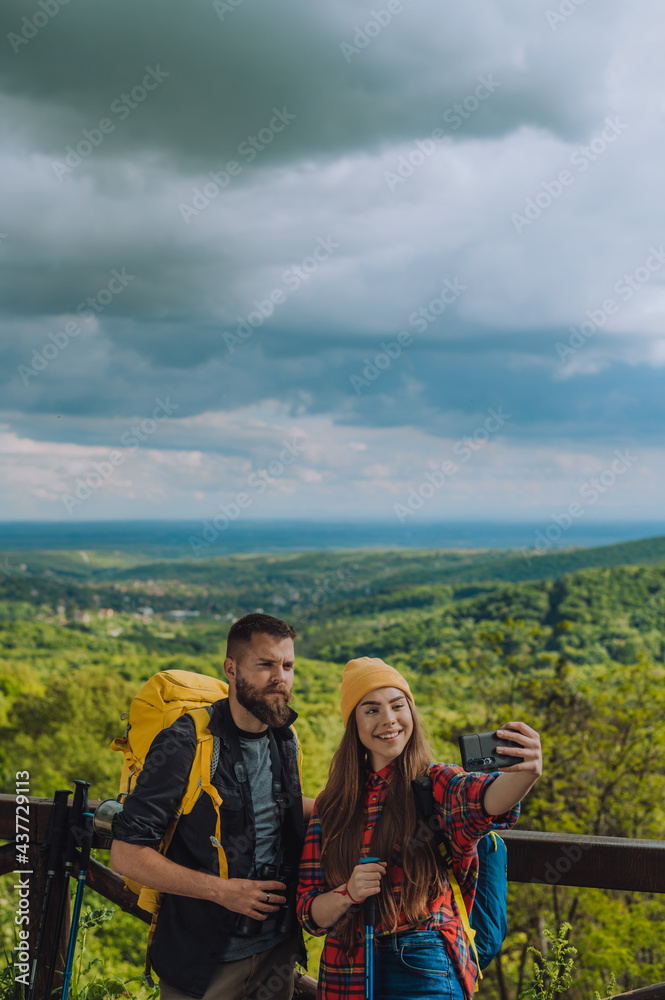 Couple of hikers taking selfie with a smartphone and using trekking poles