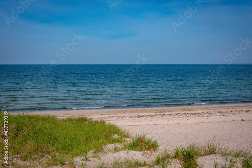 Tranquil beach seascape over the sand dune with green grasses