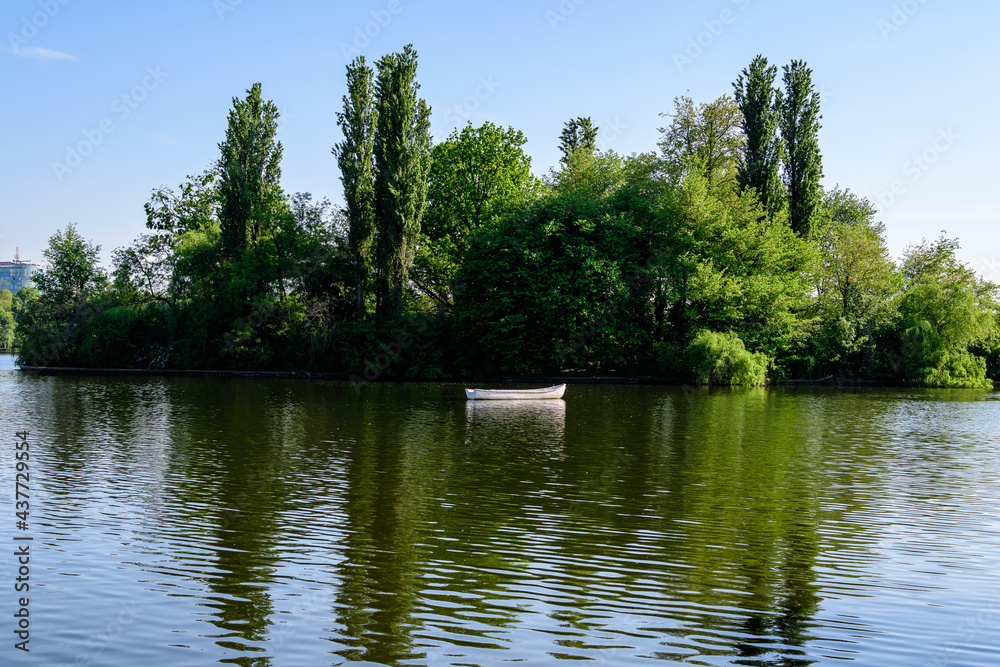 Landscape with one green island on Herastrau lake in King Michael I Park in Bucharest, Romania,  in a sunny spring day.