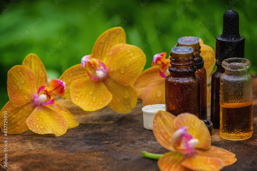 bottles with essential oils and orchid in bowl isolated on white background