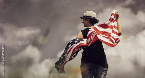 4th of July - IndWoman holding the american flag outdoors on a meadow.  4th of July - Independence day.ependence day. © belyaaa