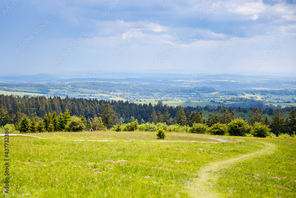 Landscape on Hoherodskopf, volcano region in Hesse, Germany. On cloudy sunny warm summer day, meadows, hills, fields and forests.