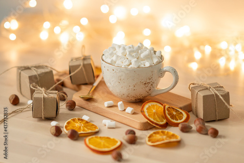 Cup of hot chocolate with marshmallows on festive background.