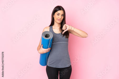 Young caucasian woman with mat isolated on pink background showing thumb down sign