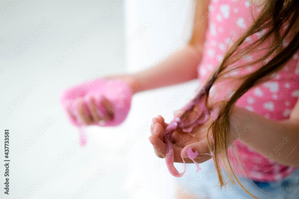 Fototapeta premium A little girl stained her hair with slime. Child hair tangled in pink slime.