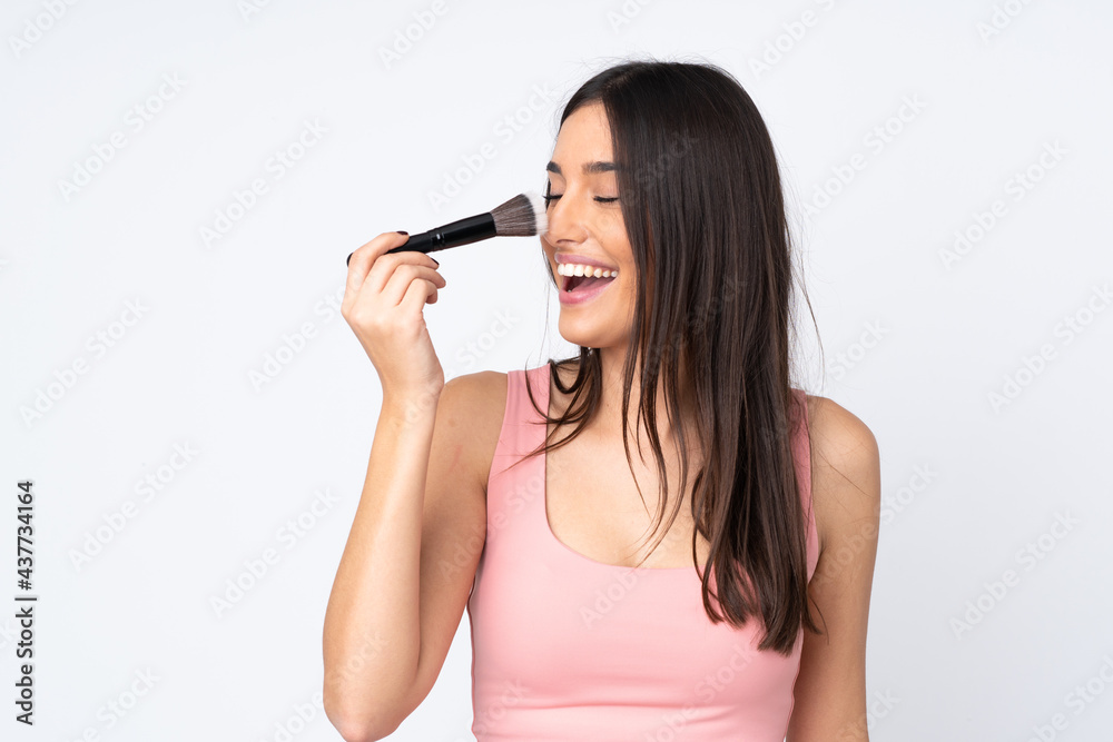 Young caucasian woman isolated on white background holding makeup brush and whit happy expression Young caucasian woman isolated on white background holding makeup brush and whit happy expression