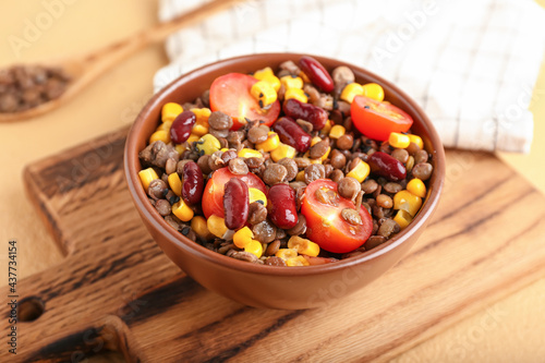 Bowl of tasty cooked lentils, beans and vegetables on table