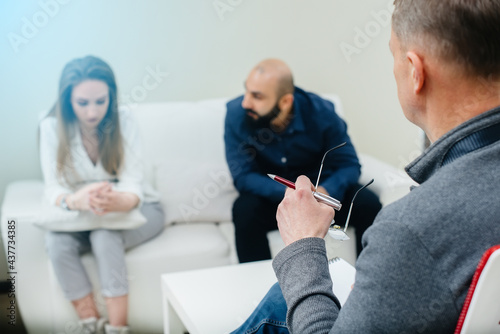 A young married couple of men and women talk to a psychologist at a therapy session. Psychology. © Andrii