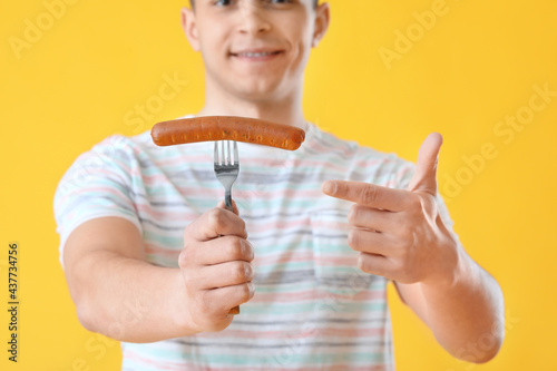 Young man with tasty sausag...