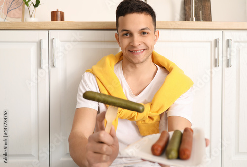 Young man with tasty sausag...