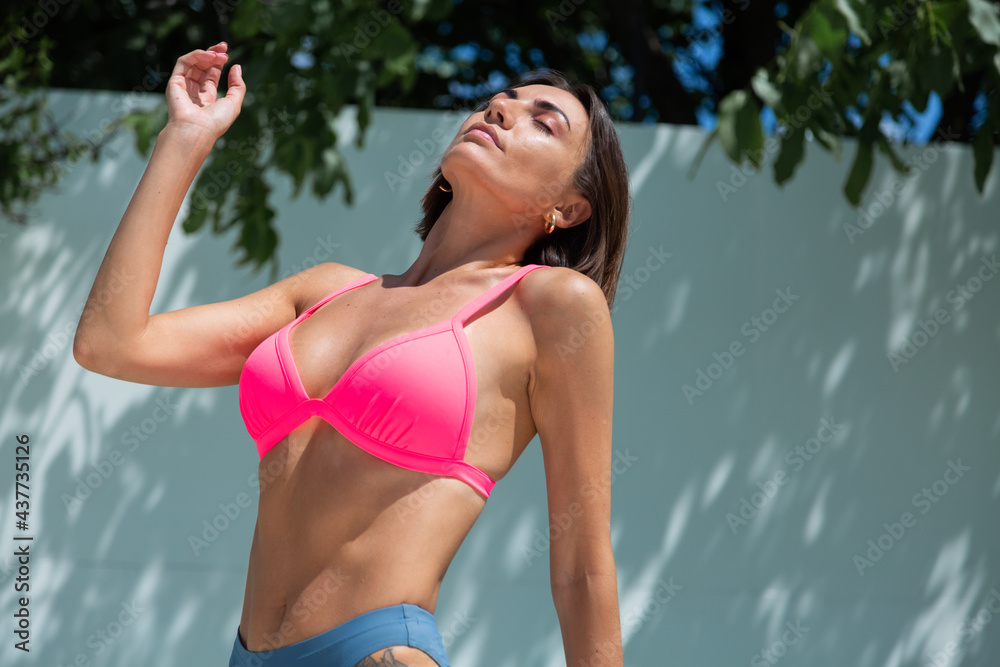Beautiful tanned fit woman in bikini in backyard posing outdoor by pool Beautiful tanned fit woman in bikini in backyard posing outdoor by pool