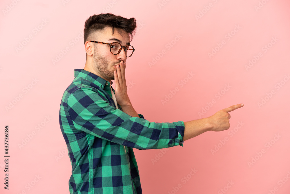 Young caucasian man isolated on pink background with surprise expression while pointing side Young caucasian man isolated on pink background with surprise expression while pointing side