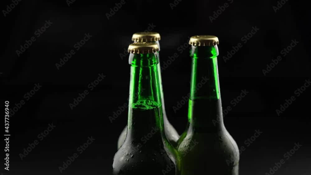 Three green glass beer bottles spinning on a black background in the dark Three green glass beer bottles spinning on a black background in the dark