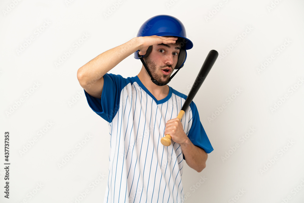 Young caucasian man playing baseball isolated on white background doing surprise gesture while looking to the side
