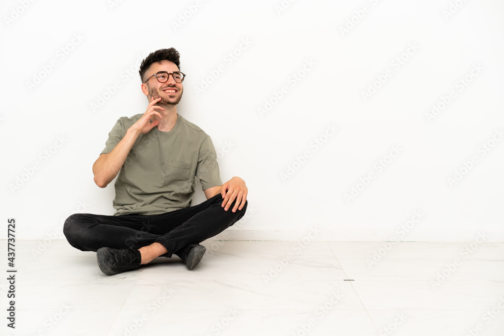 Young caucasian man sitting on the floor isolated on white background thinking an idea while looking up Young caucasian man sitting on the floor isolated on white background thinking an idea while looking up