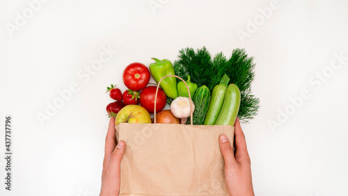 Package with various products, tomato, cucumber, pepper, greens, zucchini, vegetables, fruits in hands on a white background. The concept of home delivery of useful products. top view. copy space