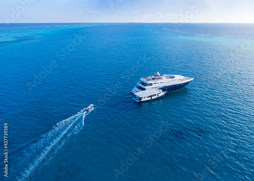Aerial view of the motor boat approaching tourist ship in the Indian ocean with a small island on the horizon © Sergey